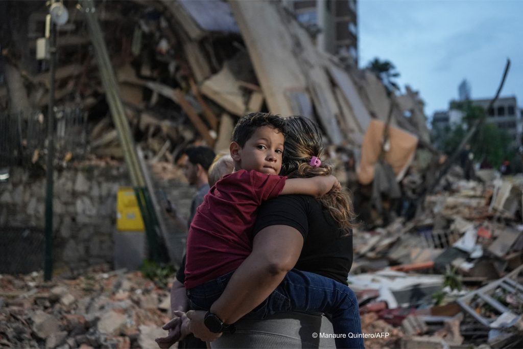 Un enfant dans les bras de sa mère sur les ruines d'une immeuble effondré durant le séisme.