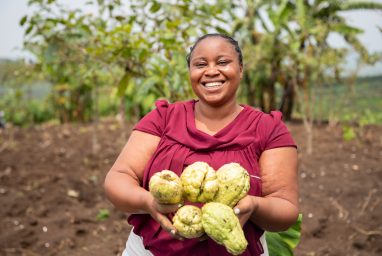 Une agricultrice tient dans fruits à la main dans un champ