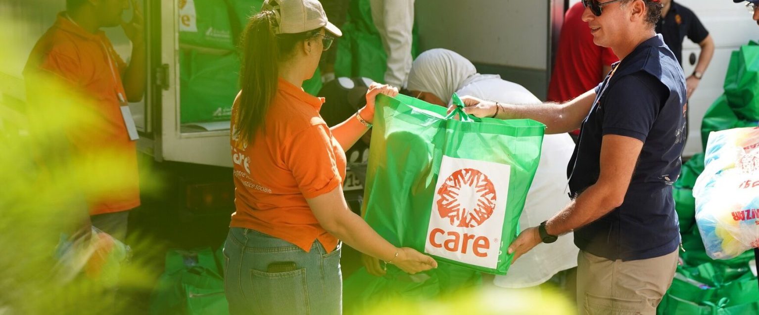 Deux membres de l'ONG CARE tiennent un sac de distribution d'aide humanitaire entre leurs mains