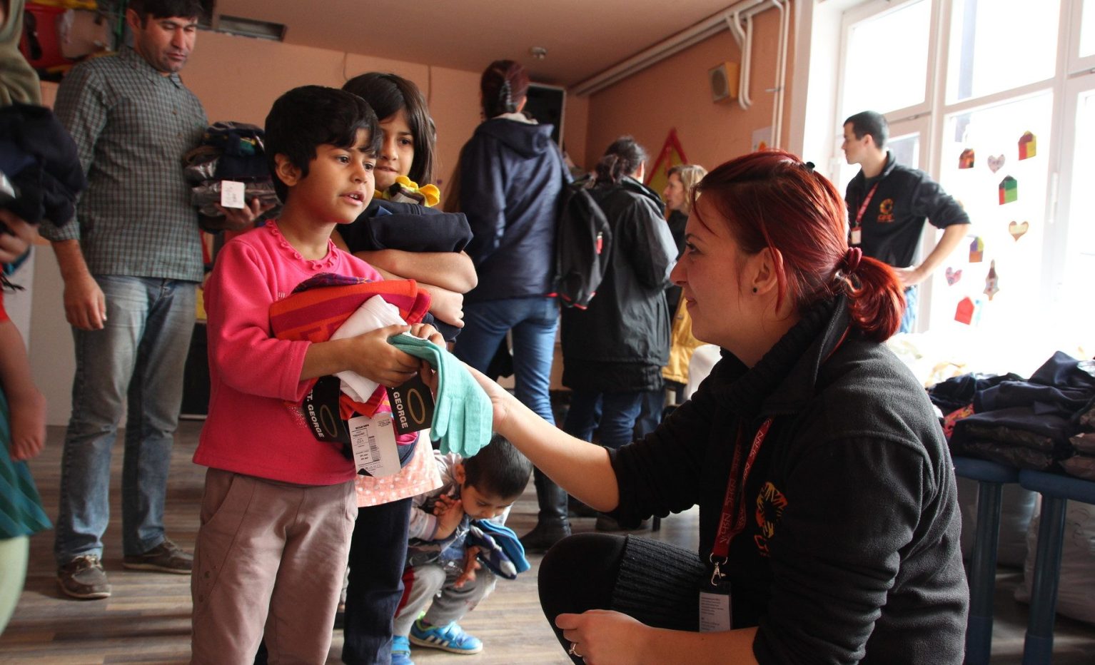 Un membre de l'ONG CARE distribue de l'aide humanitaire à un enfant.