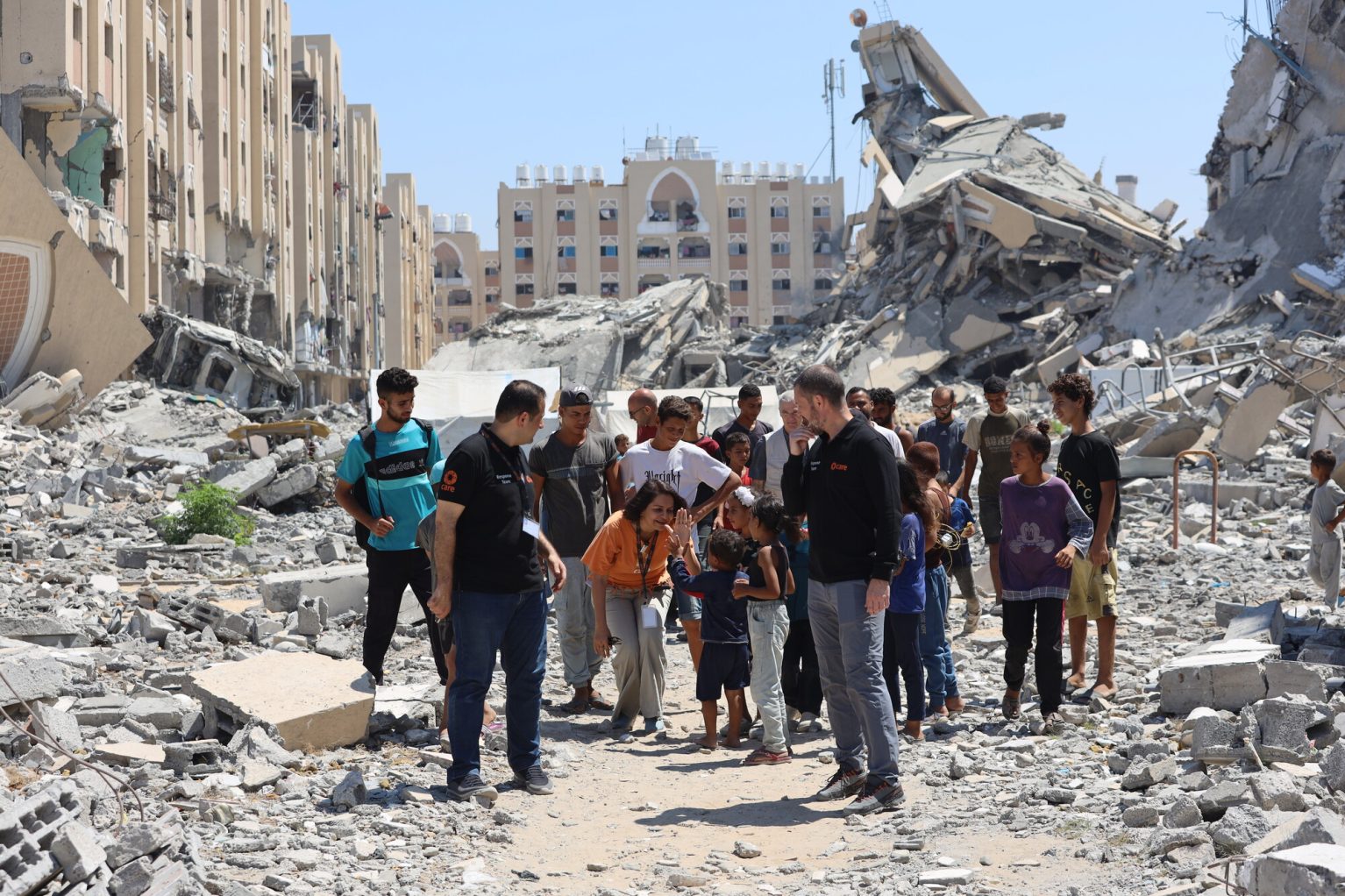 Du personnel de l'ONG CARE et des membres de la populations marchent dans les décombres des bombardements à Gaza.