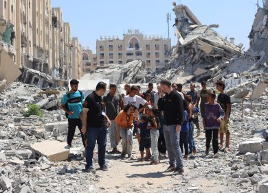 Du personnel de l'ONG CARE et des membres de la populations marchent dans les décombres des bombardements à Gaza.