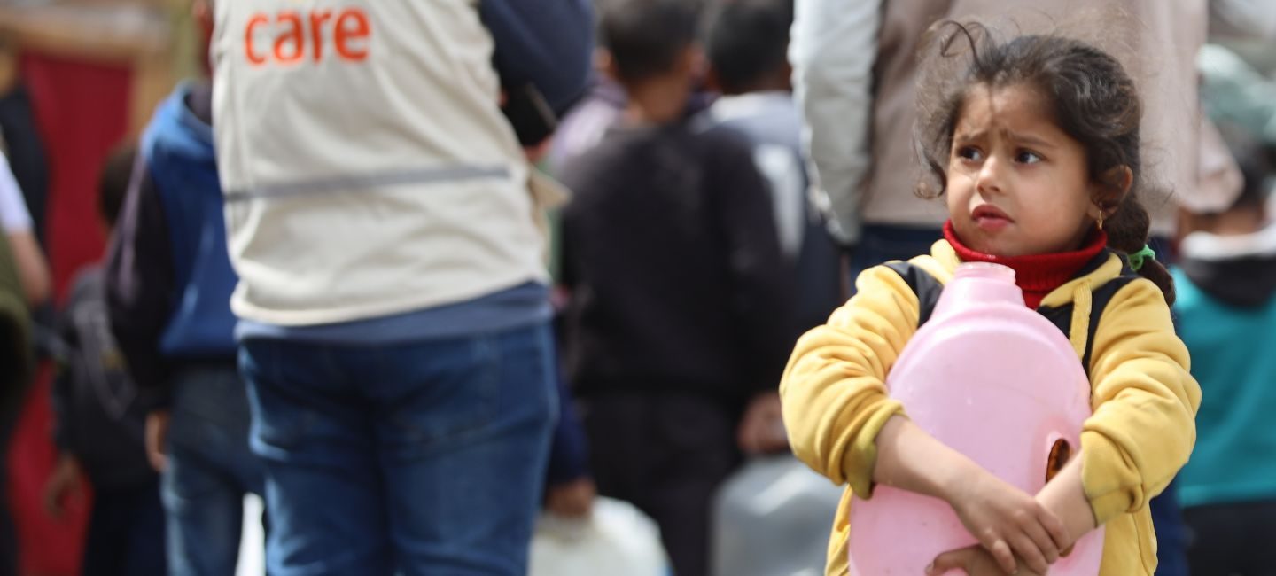 Une petite fille touchée par la guerre à Gaza tient un bidon d'eau dans ses bras