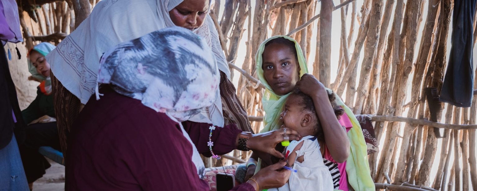 Une femme soigne un bébé réfugiée par le conflit au Soudan dans un camp au Tchad.