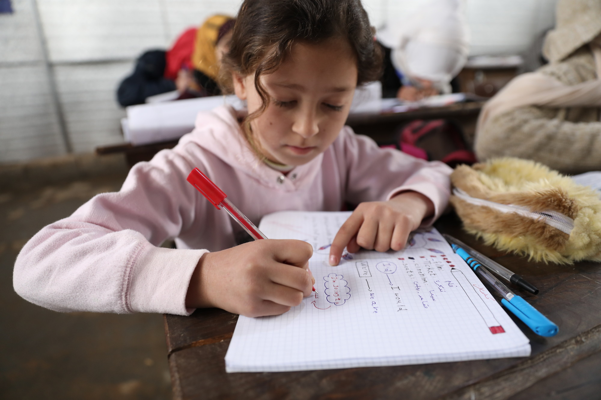 Une fille écrit dans son cahier d'école en Syrie