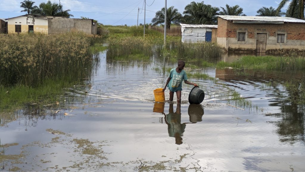 Un garçon marche dans les eaux inondées du village de Gatumba.