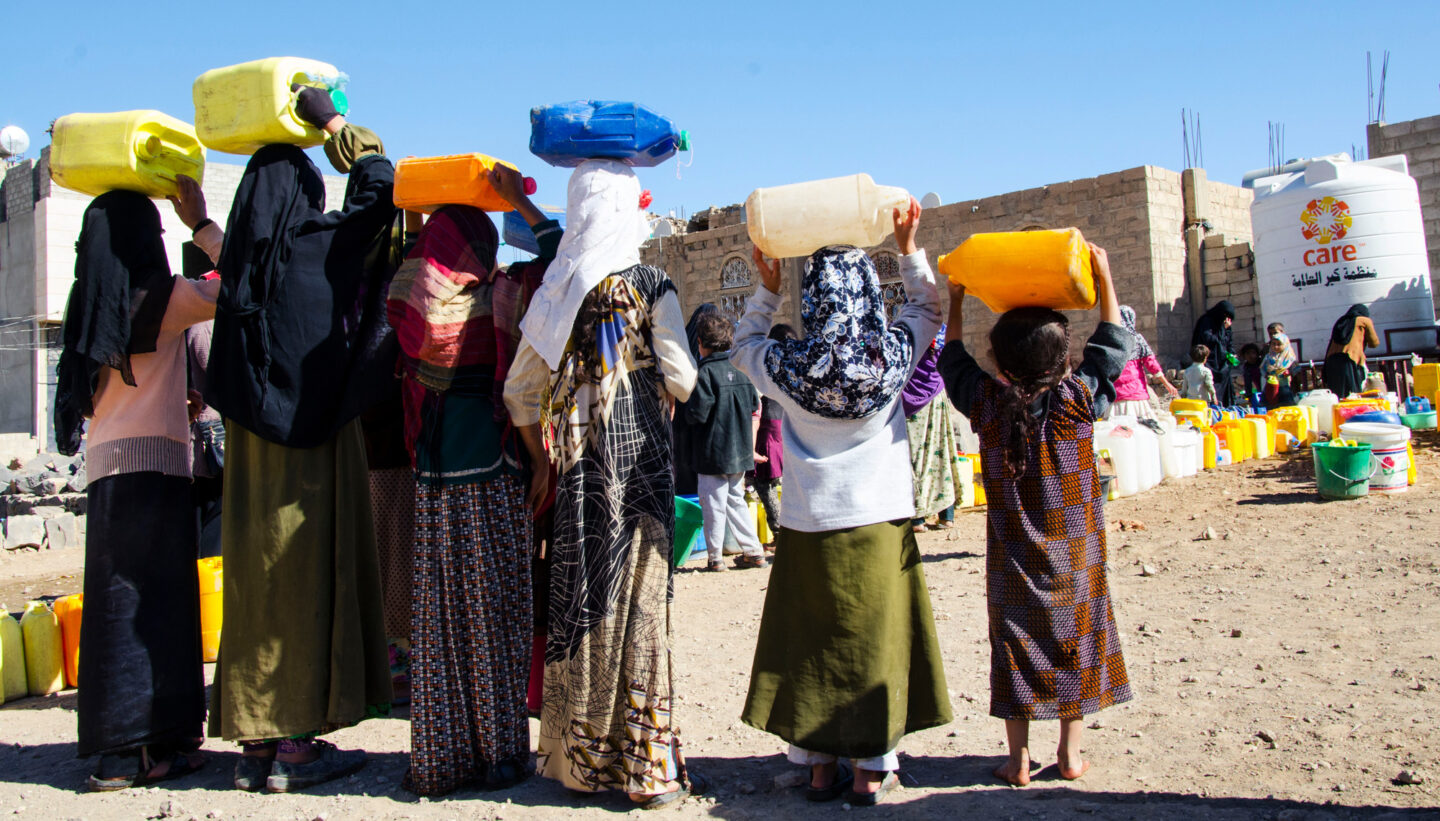 Des filles font la queue devant un conteneur d'eau de l'association CARE au Yémen
