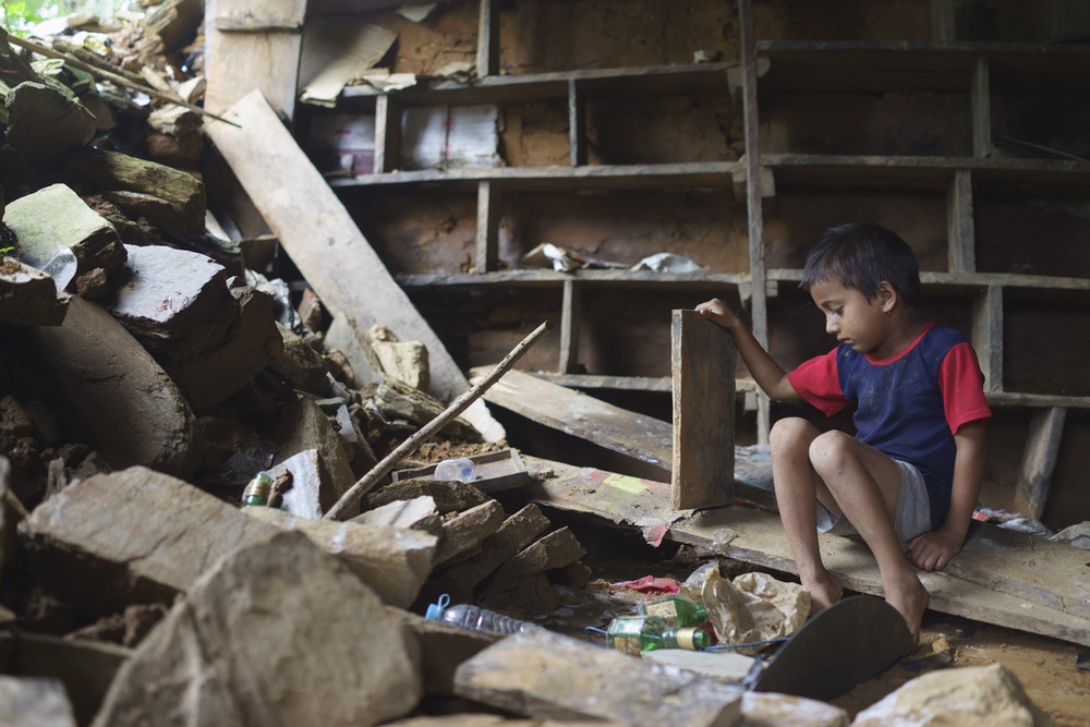Séismes Népal - Durkesh Koirala, six ans, vit dans le village de Mulpani. Il se trouve dans les décombres de son ancienne maison. Il cherche à récupérer des objets pour jouer avec ses amis.