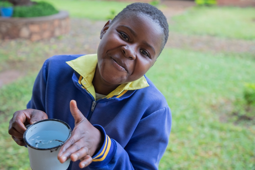Au Zimbabwe, une élève sourit et boit de l'eau