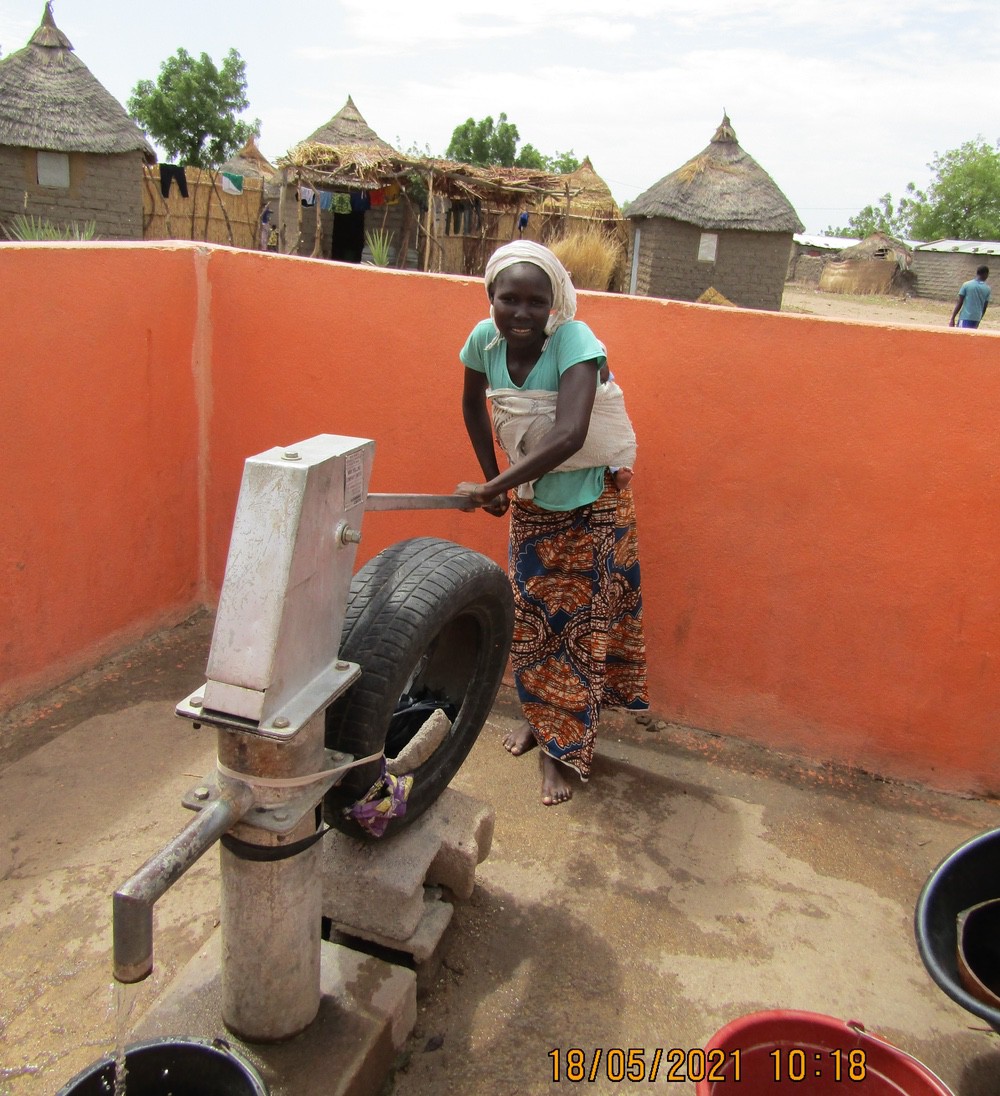 Une femme au Cameroun puise de l'eau du nouveau forage construit par l'association CARE